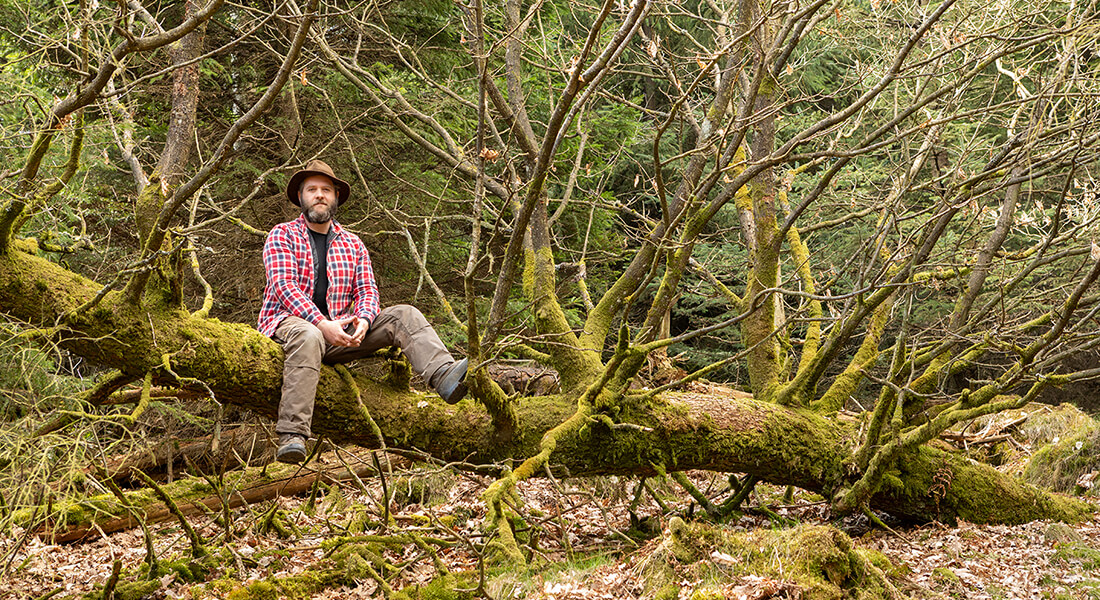 Man sitting on dead tree. Photo: Kent Pørksen